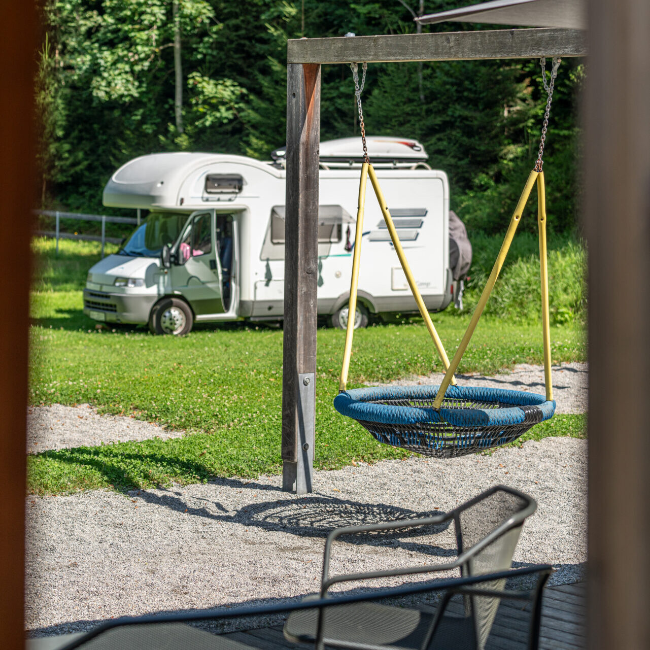 Kinderspielplatz am Campingplatz, im Hintergrund ein Wohnmobil in der Wiese